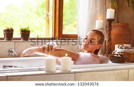 Sensual woman in bathtub relaxed, female in jacuzzi, taking bath, luxury spa resort, girl enjoying bathing with soap foam, vacation and holidays concept