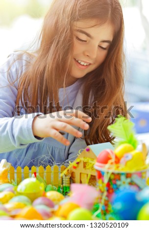 Portrait of a cute little girl playing with colorful eggs, painting and decorating, traditional Easter fun, religious holiday
