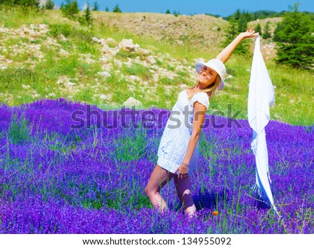 Attractive young lady wearing summer hat and dance with white shawl on floral field, fresh purple lavender flowers, relaxation outdoors