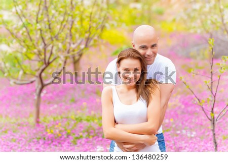 Handsome man hugging his attractive woman in spring park, beautiful nature, strong feelings, love and tenderness concept