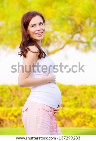 Beautiful pregnant woman walking in spring park, healthy pregnancy, springtime nature, new life concept