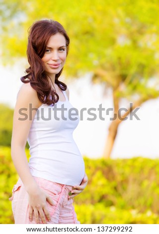 Cute expectant woman spending time outdoors in spring time, happy motherhood, healthy pregnancy, love concept