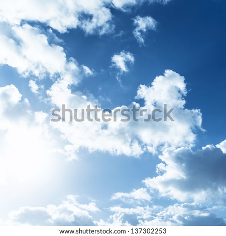 White fluffy clouds on blue sky, bright sun light, abstract natural background, summer season, meteorology concept