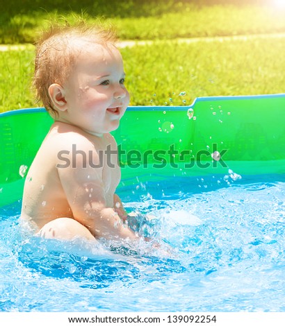 Sweet baby in the children pool on the garden on backyard, having fun outdoors, summer time activities, enjoying holidays, happy childhood concept