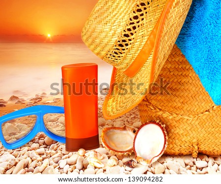 Closeup beach items on sunset on the stony seashore, hygiene accessories, snorkeling mask, sunscreen, hat, bag and towel, summer activities