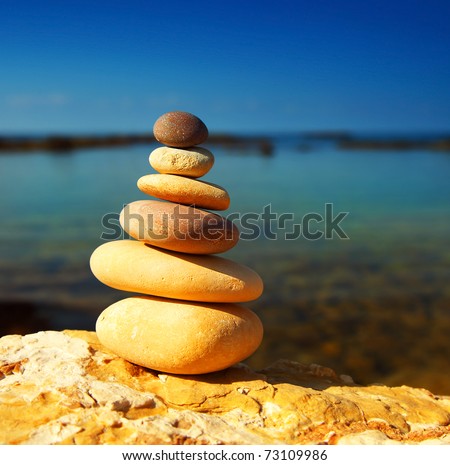 Zen spa balance stones, over blue calm sea background, conceptual image of relaxation & vacation