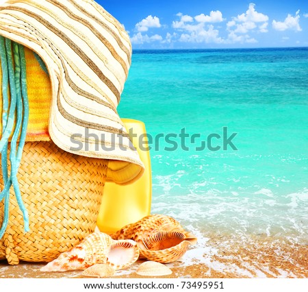 Beach items over blue sea conceptual image of summertime vacation & holidays