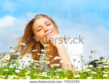 Young beautiful girl laying on the daisy flowers field, outdoor portrait, summer fun concept