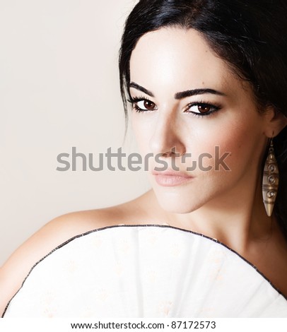 Beautiful brunette model with Chinese fan, closeup female portrait isolated on beige background