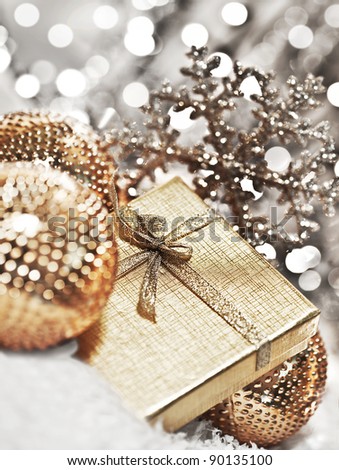 Silver gift box with baubles decorations, Christmas tree ornament for winter holidays, present with abstract bokeh shiny glowing blur lights background