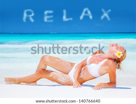 Girl relaxing on the beach with fresh frangipani flower in blond hair, taking sunbath, relaxation on luxury spa resort, summer vacation concept