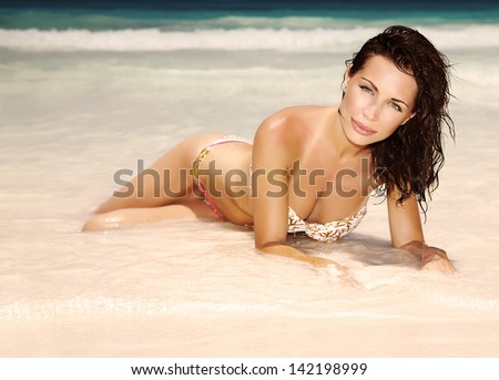 Gorgeous female lying down on the beach, sexy slim model posing on sandy coastline, luxury lifestyle, summer holidays and vacation concept
