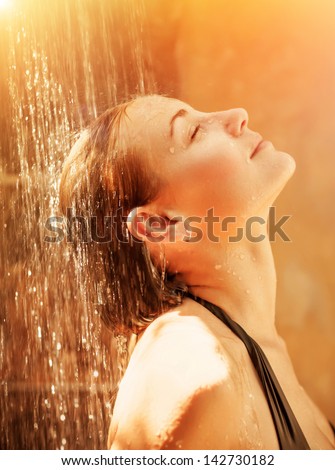Attractive female taking shower with pleasure, cute girl with closed eyes enjoying warm water spray, luxury spa resort