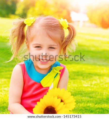 Adorable sweet child with sunflowers bouquet having fun in the garden, little girl enjoying summer nature, happiness concept
