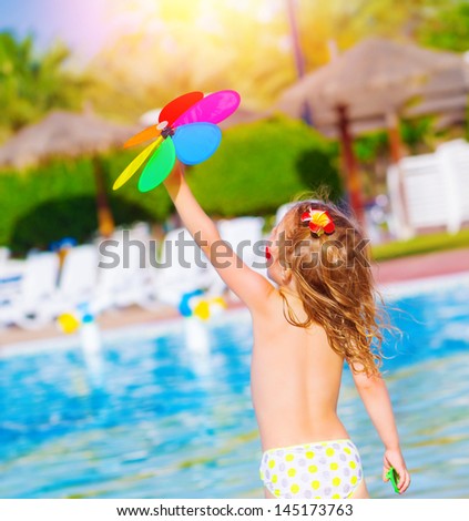 Little baby girl having fun in water park, sweet child play with colorful flower toy, enjoying summer holiday, resting near poolside