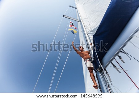 Handsome man working on sailing ship, cute sailor fixed sail, young cheerful skipper on the yacht, active lifestyle, summer vacation and traveling concept