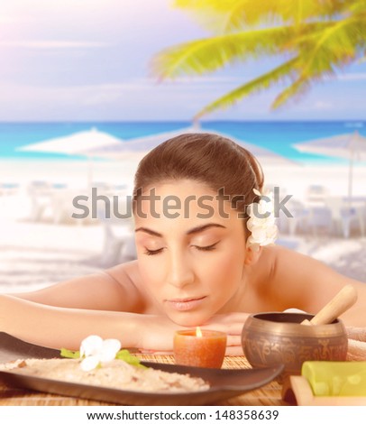 Closeup portrait of pretty woman lying down on massage table on the beach, closed eyes, luxury spa resort, tropical vacation, summer holidays
