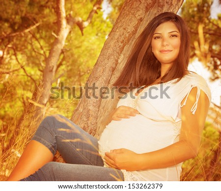 Expectant woman having fun outdoors, relaxation in beautiful autumnal park, weather changes, young family and new life concept