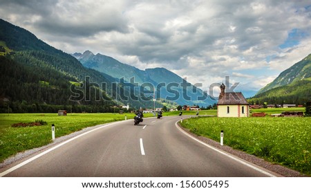 Bikers on mountainous highway, Europe, Austria, Alps, road along little village, driving motorcycle, extreme sport, active lifestyle concept