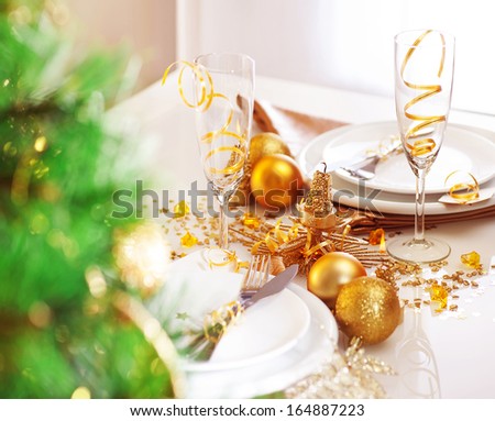 Picture of romantic holiday dinner, luxury table setting and decorated Christmas tree in the restaurant, two glasses for traditional New Year alcohol drink, champagne, xmas white utensil