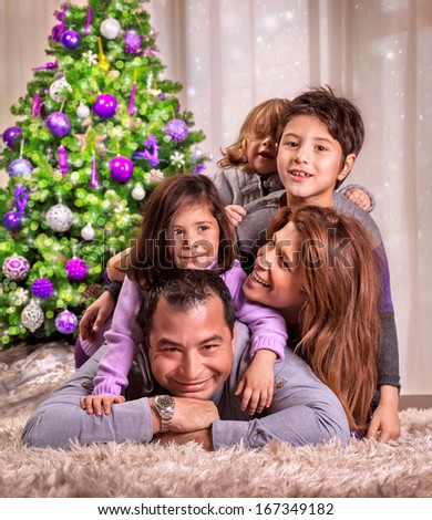 Portrait of happy arabic family lying down near beautiful decorated Christmas tree, celebrating holiday at home, happiness concept