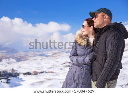 Happy couple in snowing mountains, active lifestyle, winter vacation, luxury wintertime resort, loving family, cold weather