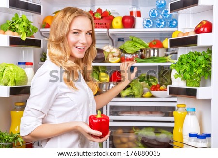 Woman chosen milk in opened refrigerator, cool new fridge full of tasty organic nutrition, female preparing to cook, healthy eating concept