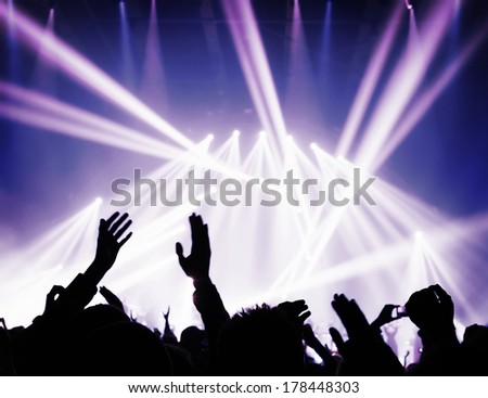 Music concert, silhouette of raised up  people hands in bright blue lights, dancing club, night performance, active life concept