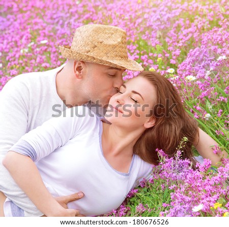 Handsome guy hugging and kissing his beautiful girlfriend, relaxation outdoors, strong gentle feelings, spring season, young family concept