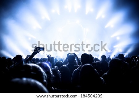 Music concert, many people enjoying evening in night club, live sound, musicians on the stage, popular band, fun and joy concept, New Year celebration
