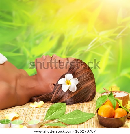Beautiful young african woman enjoying day spa, lying down on massage table with closed eyes, take medical treatment outdoors, luxury spa resort