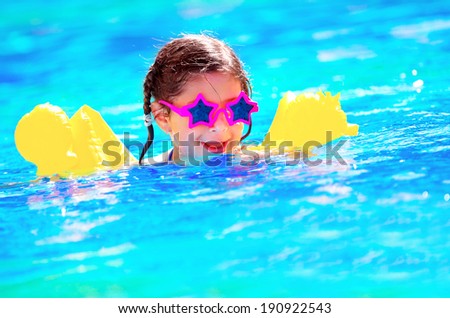 Cute little baby swimming in the pool, wearing funny sunglasses, enjoying summer weekend in aquapark, holidays and vacation concept