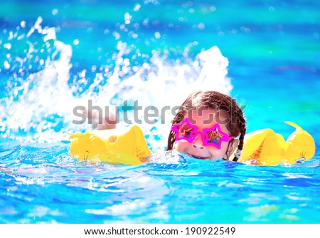 Cute little baby swimming in the pool, wearing funny sunglasses, enjoying summer weekend in aqua park, holidays and vacation concept