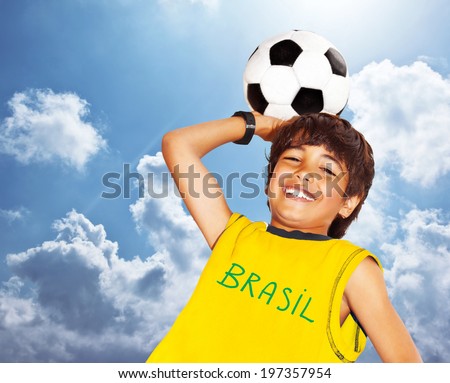 Boy playing football outdoor happy child teen goalkeeper enjoying sport game holding ball portrait of a preteen smiling and having fun kids activities little footballer over blue sky background Boy playing football outdoor happy child teen goalkeeper enjoying sport game holding ball portrait of a preteen smiling and having fun kids activities little footballer over blue sky background