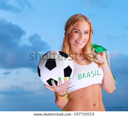 Happy fan of Brazilian football team, cheerful pretty girl on stadium cheering in support, holding up big national flag of Brazil, active people traveling to watch football games