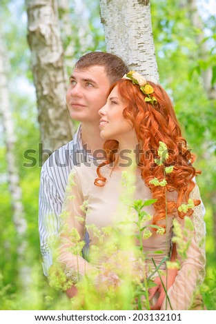 Portrait of cute cheerful couple hugging in the forest and looking in one side, happy wedding day, romantic feelings, new family concept