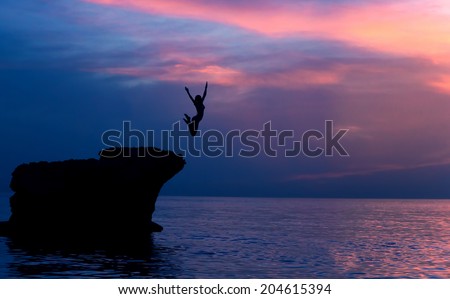 Brave girl jumping from the rocks in the evening on beautiful purple sunset background, summer adventure, freedom concept