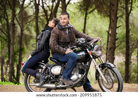 Bikers couple resting in the forest, two models posing on the motorcycle, active lifestyle, fashion style, romance and extreme concept