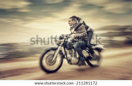 Two happy people riding on motorcycle, slow motion effect, grunge style photo, romantic relationship, speed and adventure concept