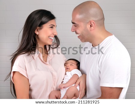 Portrait of cheerful young parents holding on hands cute newborn daughter, healthy childhood, happy parenthood concept