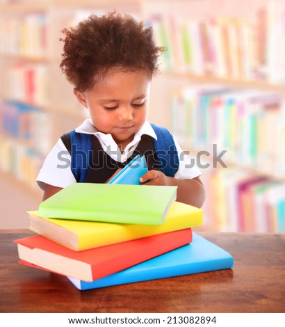 Little clever preschooler in the library, reading books, cute African American boy preparing to go to first grade, enjoying study, back to school