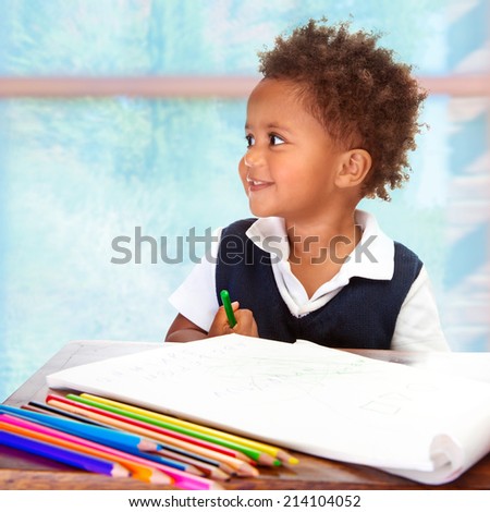 Portrait of cute little African preschooler on drawing lesson, painting with many colorful pencils, elementary education concept