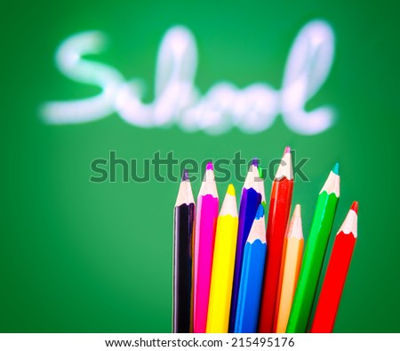 Colorful pencils on green chalkboard background, soft focus of handwriting word, lesson of art, back to school concept