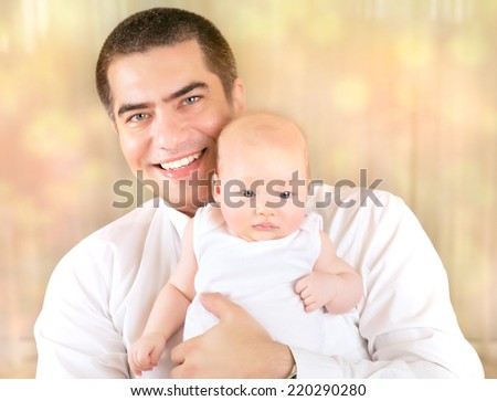 Portrait of father with baby at home, cheerful young daddy holding newborn child on hands over blur bokeh background, happy family concept