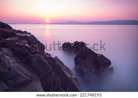 Purple sunset over sea, majestic rocks in the fog, beautiful beach landscape, wonderful panoramic scene in Europe, travel and tourism concept