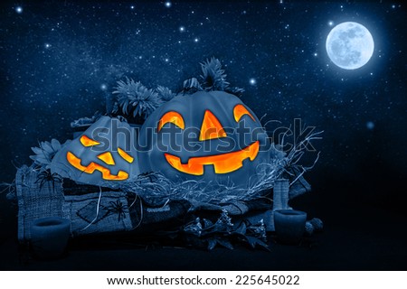 Halloween night decorations, scary carved pumpkin head glowing in dark starry night, full moon, traditional October holiday, horror concept