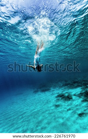 Active young female dancing underwater, enjoying summer vacation in blue transparent water, dive to the bottom of sea, enjoyment and freedom concept