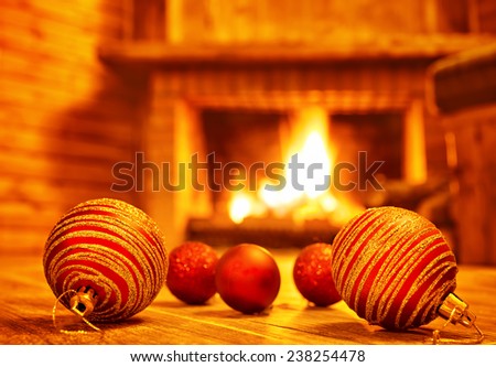 Cozy Christmas eve at home, beautiful red glass balls on the floor on fireplace background, luxury Christmas tree decoration