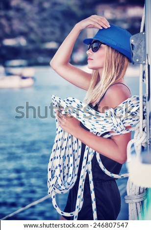 Sexy girl standing on sailboat with rope, vintage style photo of attractive sailor girl, active lifestyle, summer vacation concept
