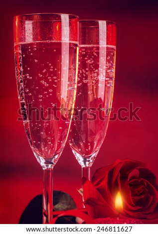 Valentine day dinner, two elegant glass of champagne decorated with red rose and candle, romantic still life, love and passion concept